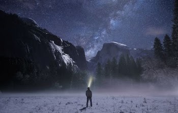 person wearing headlamp facing towards snow mountain