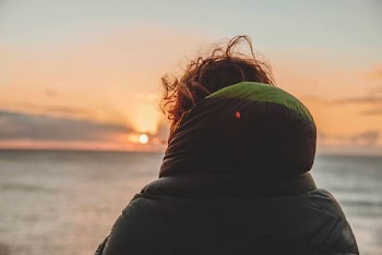 person wearing hooded jacket watching golden hor