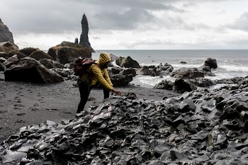 Person Wearing Hoodie Touching Stone in Seashore