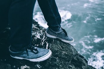 person wearing low-top sneakers on cliff