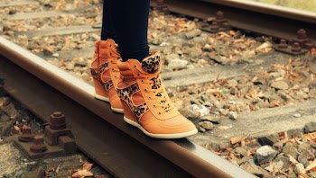Person Wearing Orange and Black Wedge Shoes on Train Railway during Daytime