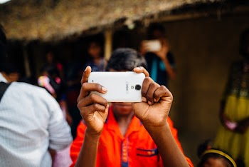 Person Wearing Orange Shirt Holding Smartphone