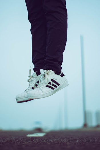 Person Wearing Pair of White Adidas Superstar Shoes