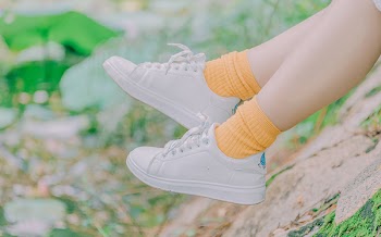 Person Wearing Pair of White Low-top Sneakers and Orange Crew Socks