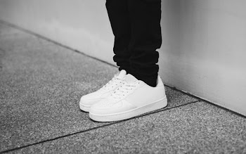 person wearing pair of white sneakers standing near wall