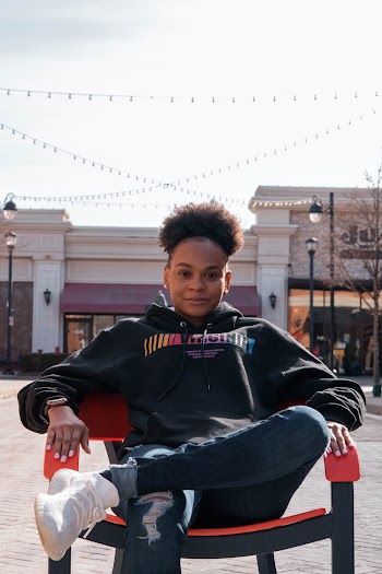 Person Wearing Pullover Hoodie and Jeans Sitting on Armchair
