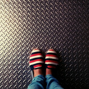 Person Wearing Red-and-multicolored Slip-on Shoes Standing on Gray Metallic Diamond Plate