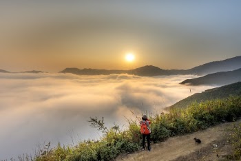 Person Wearing Red Backpack Facing Sea of Clouds