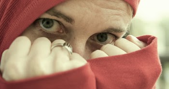 Person Wearing Red Hoodie and Gold-colored Ring Covering Face With Both Fists