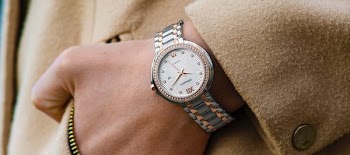 person wearing round gold-colored analog watch with link band