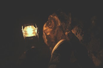 Person Wearing Sneakers Sitting Near Kerosene Lamp