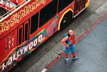 Person Wearing Spider-man Costume Standing Beside Red Bus