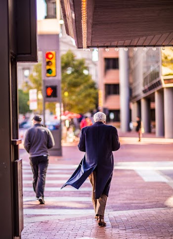 Person Wearing Trench Coat While Walking on Sidewalk