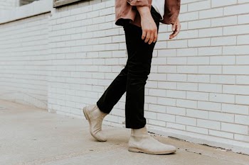 person wearing white leather chelsea booties and black pants