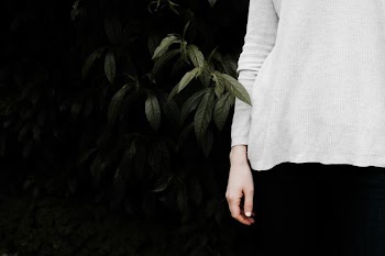 person wearing white long-sleeved shirt standing near green leaf bush