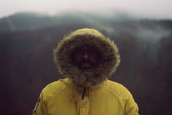 person wearing yellow parka jacket near mountain