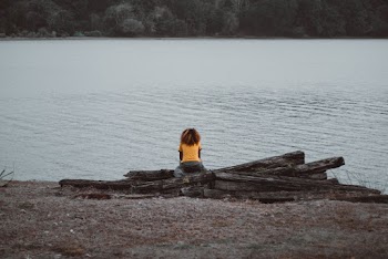 Person Wearing Yellow Shirt Sitting Near Lake