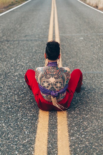 Person With Calavera Tattoo on Back Sitting in Middle of Street