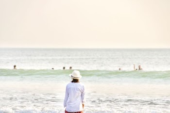 person with hat standing front of sea at daytime