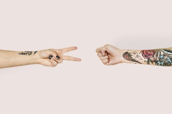 Person With Tattoo Playing Paper, Scissor and Stone