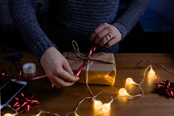 Person Wrapping Gift on Table