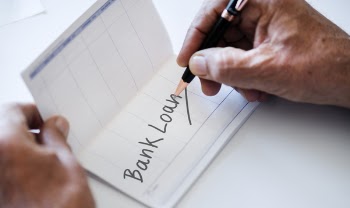 Person Writing Bank Loan on Paper