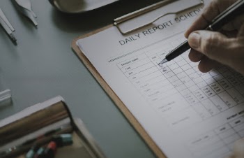 Person Writing On Daily Report Schedule 