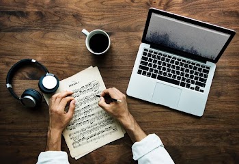 person writing on musical note near MacBook Pro