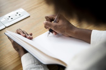 Person Writing on Notebook