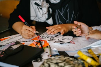 Person Writing on Paper on Top of Table