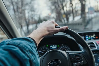 persons hand holding Subaru steering wheel in the car