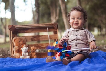 Photo of a baby boy Siting on Blue fabric holding a toy