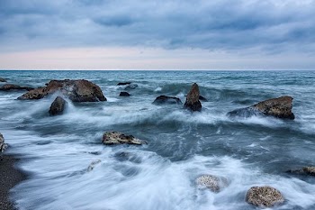 photo of a dancing waves with rocks