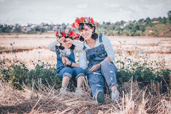 Photo of a Girl and a Woman in Blue Denim Overall Sitting on Grass