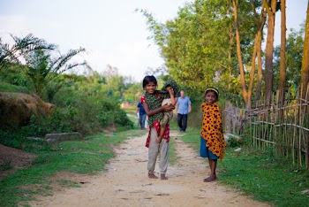 Photo of a Girl Standing While Carrying a Baby