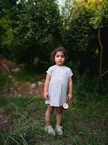 Photo of a Little girl standing in front of trees