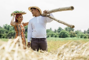 Photo of a Man Carrying Bamboo Poles Near Woman