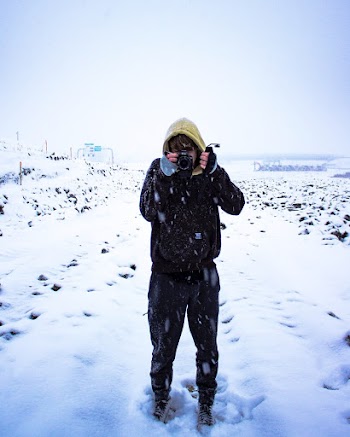 Photo of a Man Holding a Camera on Snow Covered Ground