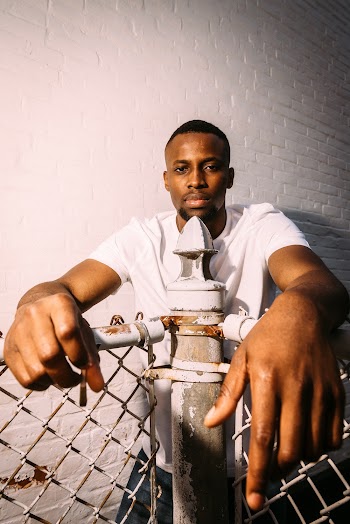 Photo of a Man Holding on Metal Fence
