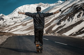Photo of a Man I the Middle of Road Using Skateboard