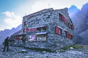 Photo of a Man in Black Sweater Standing in Front of Gray Concrete Building