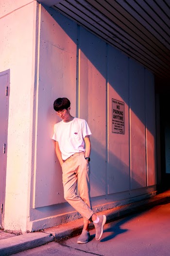 Photo of a Man in White Crew-neck T-Shirt and Brown Trousers Leaning on a wall