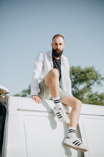 Photo of a Man in White Long Sleeves Shirt Sitting on White Panel