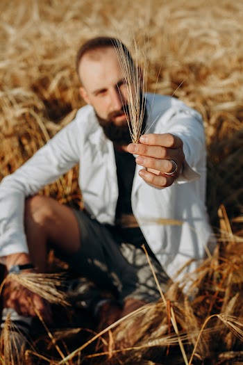 Photo of a Man Sitting Holding a Wheat 