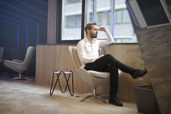 Photo of a Man Sitting Near the Windoww