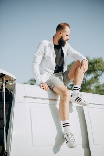 Photo of a Man Sitting on Top of a White Van