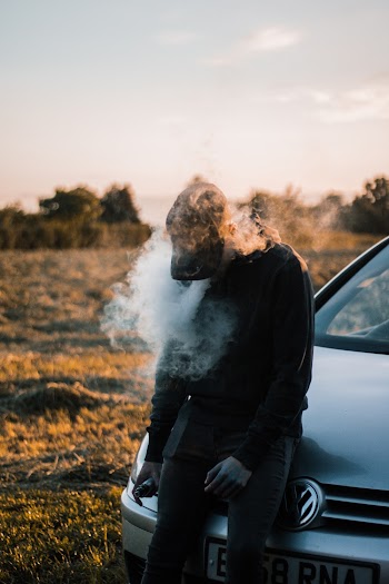 Photo of a Man Sitting on Vehicle Hood