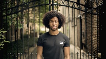Photo of a Man Standing Beside Black Gate