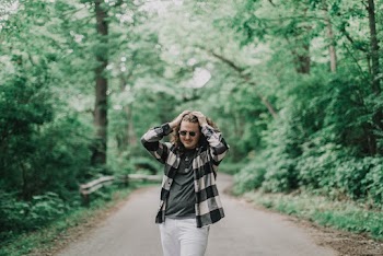 Photo of a Man Standing on a Road Surrounded by Trees