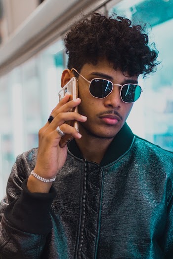 Photo of a Man Wearing a Black Bomber Jacket Using a Smartphone
